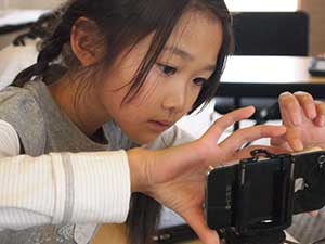 Little girl using a phone in a blended learning classroom