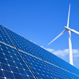 solar panels with a windmill and blue sky in the background