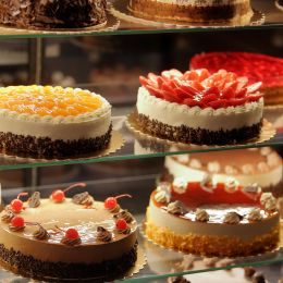 cakes with fresh fruit on top displayed in a bakery store