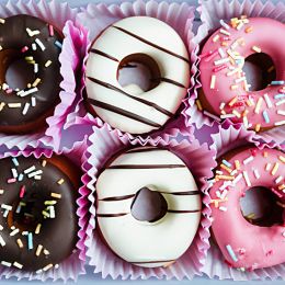 six doughnuts with pink black and white frosting