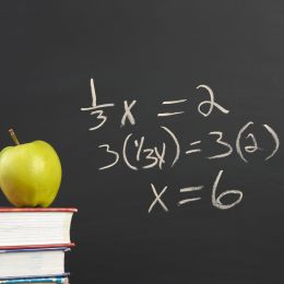 math expression written on a black chalkboard with an apple in the foreground