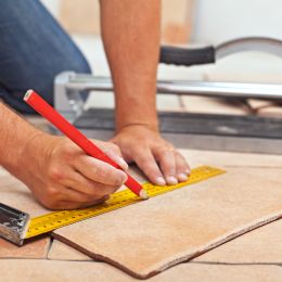 contractor making markings on tiles using a ruler and pencil