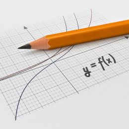 equation showing a curved graph on graph paper with a pencil on top