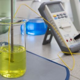 yellow liquid in a flask with testing device and blue liquid in background