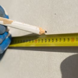 pencil mark being made on wall using measuring tape