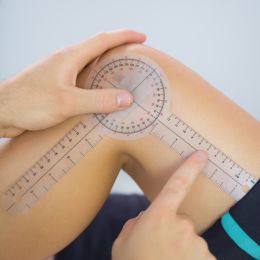 person holding a protractor up to their knee