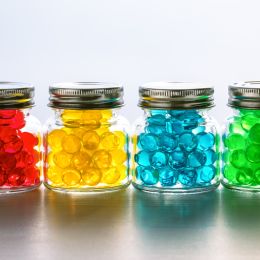 colorful marbles in four small glass jars