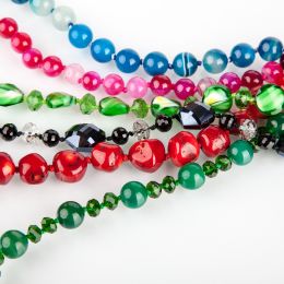 zoomed in view of necklaces made of beads in green red black blue and pink