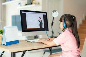 Girl listening to her teacher on a computer