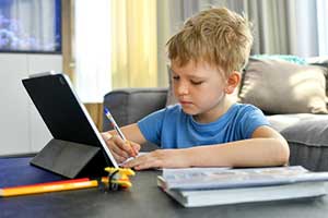 Boy doing his homework at home as part of the flipped classroom blended learning model