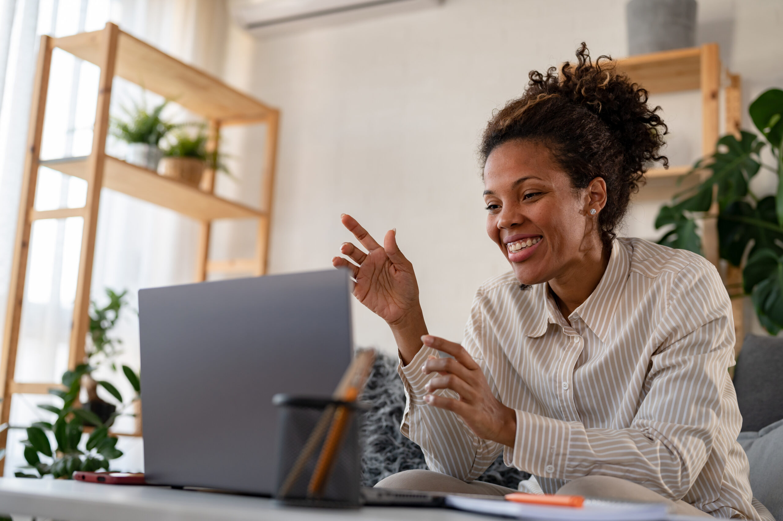 Smiling teacher preparing for back-to-school with a laptop in a cozy classroom setting